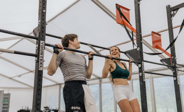 Man and woman exercising with pull-ups in an indoor gym, showcasing fitness and strength.